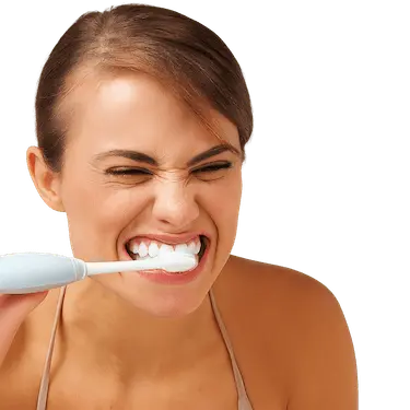 Mujer cepillándose los dientes con demasiada fuerza, ejemplo de técnica de cepillado incorrecta