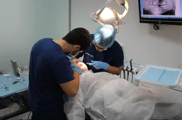 Clínica dental de confianza con cirujano realizando tratamiento odontológico seguro
