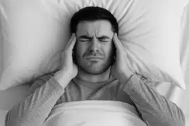 Hombre con fatiga matutina causada por apretar los dientes durante el sueño (bruxismo)