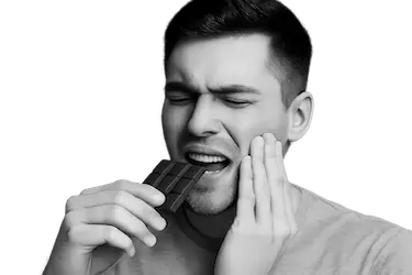 Persona con dolor dental al consumir alimentos dulces o ácidos por sensibilidad dental