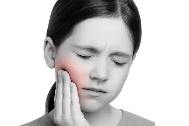 Niña con dolor dental en la mejilla por caries en una muela sin selladores dentales