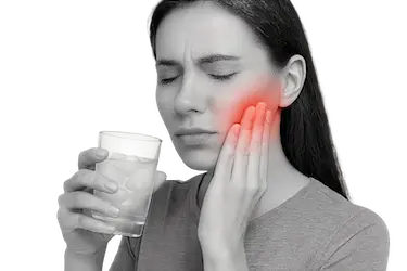 Mujer con dolor dental al beber frío, síntoma de infección bucal o flemón dental