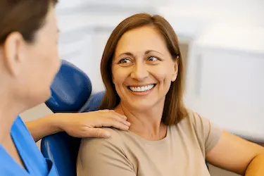Mujer sonriente en consulta odontológica tras injerto de hueso dental en clínica Dr. Ferrer Madrid