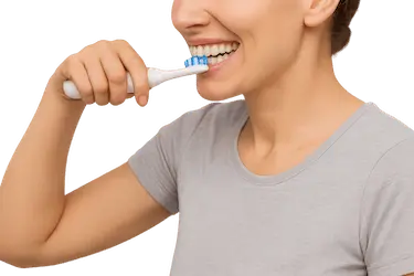 Mujer cepillándose los dientes con cepillo eléctrico para prevenir manchas y dientes amarillos
