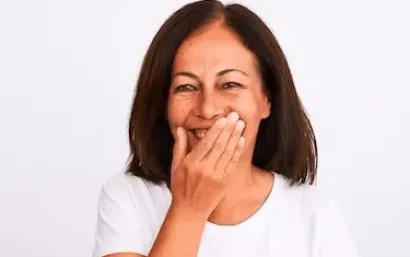 Mujer de mediana edad tapándose la boca al sonreír por la ausencia de un diente