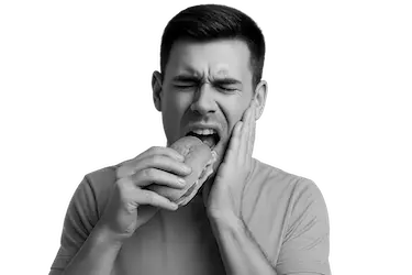 Persona con dolor al cepillarse los dientes debido a sensibilidad dental