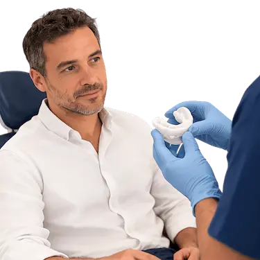 Paciente en consulta dental observando un dispositivo de avance mandibular para ronquidos